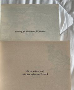 two pieces of paper with words on them sitting on top of a white bed sheet