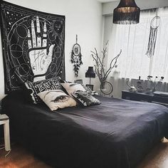 a black and white bedroom with a large tapestry hanging on the wall above the bed