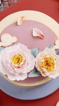 a cake decorated with flowers and seashells on a red tableclothed surface