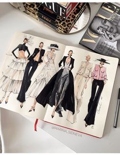 an open book with fashion illustrations on it next to a pen and pencil drawing machine