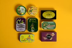 six different tins of various types on a yellow background