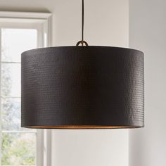 a black lamp hanging from a ceiling in a living room with white walls and windows