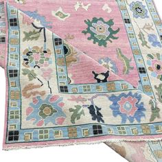 a pink and blue rug with floral designs on the bottom, in front of a white background