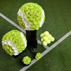 two vases with flowers and tennis balls on the grass