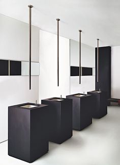 a row of black and white urinals sitting next to each other in a room