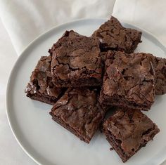 a white plate topped with chocolate brownies on top of a cloth covered tablecloth