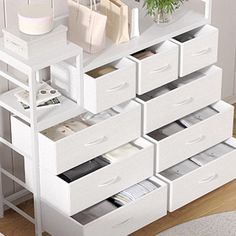 a white shelf filled with lots of drawers next to a plant on top of a table