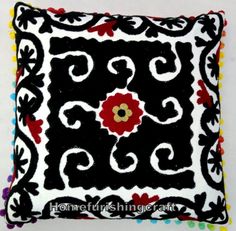 a decorative black and white pillow with colorful pom poms on the bottom corner