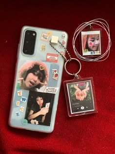 a cell phone case and keychain are laying on a red surface with two photos attached to it