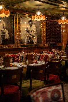 a restaurant with pictures on the wall and tables in front of them, along with red upholstered chairs