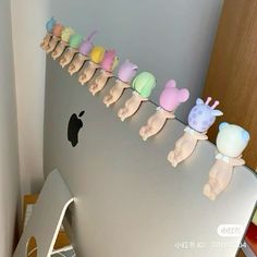 there are many small toy animals lined up on the wall next to an apple computer