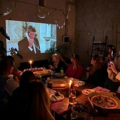 a group of people sitting around a table with pizza and drinks in front of them