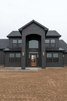 a large black building with two doors and windows on the front door is shown in an empty lot