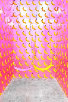 a pink room with yellow bananas hanging from it's ceiling and some chains on the wall