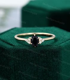 a black diamond ring sitting on top of a green velvet box