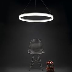 a chair sitting under a circular light fixture