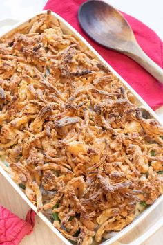 a casserole dish with meat and vegetables in it next to a red napkin