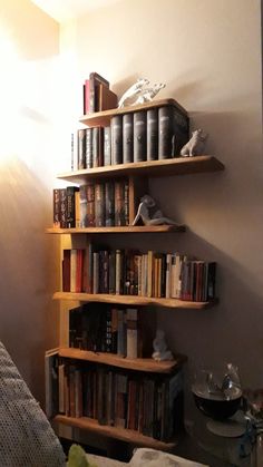 a bookshelf filled with lots of books next to a bed