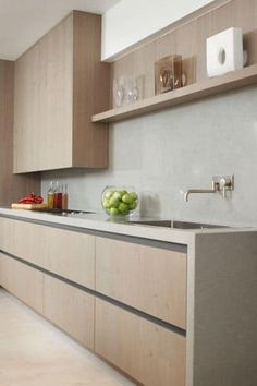 a modern kitchen with wooden cabinets and counter tops, along with fruit on the counter