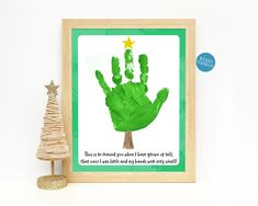 a green handprint is displayed in front of a small christmas tree with a star on top