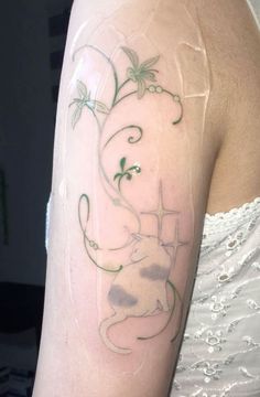 a woman's arm with an elephant and vines tattoo on the back of her shoulder