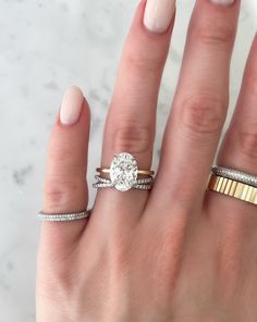 a woman's hand with three different rings on it and one has a diamond in the middle