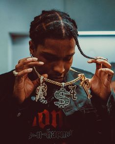 a man with dreadlocks holding up his necklace