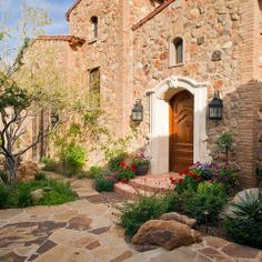 a stone house with flowers in the front yard