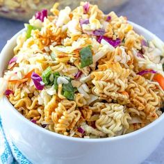 a bowl filled with noodles and vegetables on top of a blue cloth next to a container