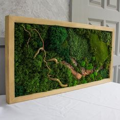 a moss covered wall with a river running through it and trees in the middle, on top of a white table cloth