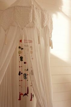 a canopy bed with white curtains and tassels hanging from it