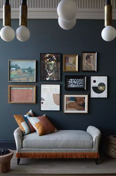 a living room with blue walls and pictures on the wall, including a gray couch