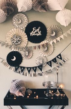 some paper fans are hanging on the wall above a table with candles and other decorations