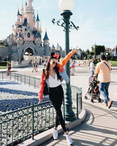 a woman standing next to a lamp post in front of a castle