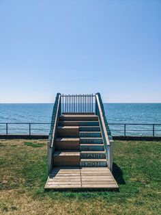 stairs lead down to the beach with water in the background and blue sky above them