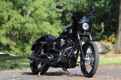 a black motorcycle is parked on the side of the road near some trees and grass