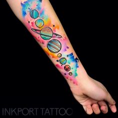 an arm tattoo with the planets and stars painted in watercolor on it's side