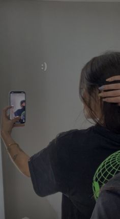 a woman is holding up her cell phone to take a selfie in the mirror