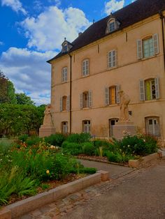 an old building with lots of windows and plants in the foreground, on a cloudy day