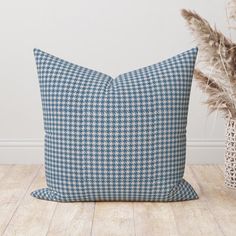 a blue and white pillow sitting on top of a wooden floor next to a plant