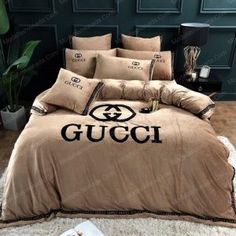 a bed with a gucci logo on the comforter and pillows in front of it