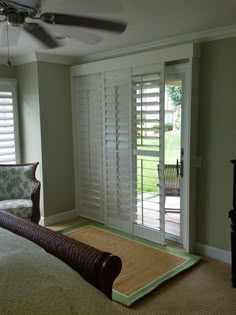 a bedroom with green walls and white shutters