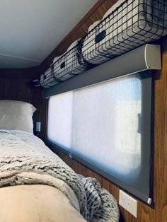 a bed in a small room with a window on the side and a basket hanging from the headboard