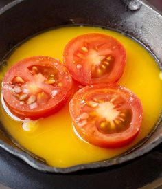 three tomatoes are being cooked in a frying pan with oil on the stove top