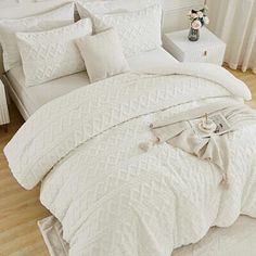 a bed with white comforter and pillows in a room