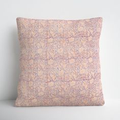 a pink and blue pillow sitting on top of a white table next to a wall