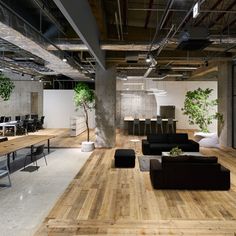 an office with wood flooring and black couches in the center, surrounded by glass walls