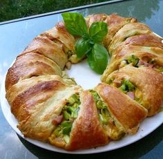 a croissant on a white plate with green leafy garnishes