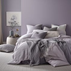 a bedroom with purple walls and grey bedding