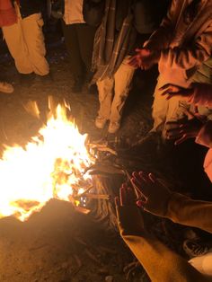 people standing around a fire with their hands on it